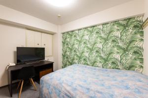 横滨Yokohama Sakuragicho Town Hotel的一间卧室配有一张床和一张书桌及电视