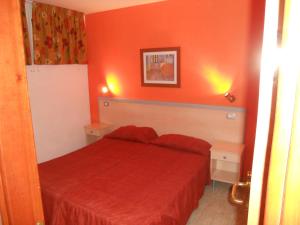 英格兰海滩绿色公园公寓酒店的红色的卧室配有红色的床和两张桌子