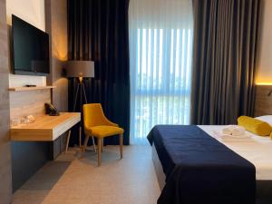 斯洛文尼亚比斯特里察莱昂纳多酒店的酒店客房配有一张床、一张书桌和一台电视。