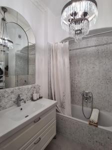 维希RoomChic - Les Ambassadeurs的一间带水槽、浴缸和吊灯的浴室