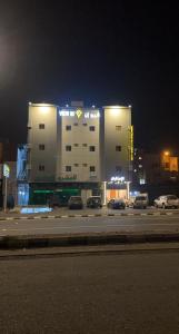 艾卜哈فيو إن للشقق الفندقية - المحالة的一座有汽车在晚上停在停车场的建筑