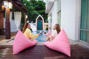 芭堤雅市中心Twenty Two Pool Villa的两名女性坐在带粉红色枕头的庭院