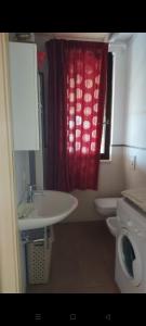 莱西纳Villa Medi的一间带水槽、卫生间和红色窗帘的浴室