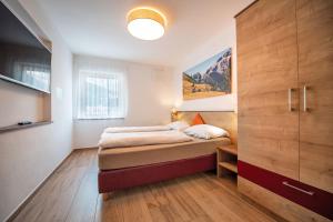 奥蒂塞伊Apartments Cesa Ploner的一间卧室配有一张床和一个大型木制橱柜