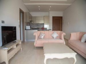 莫纳斯提尔Splendide appartement au PALM LAKE RESORT的客厅配有粉红色的沙发和电视