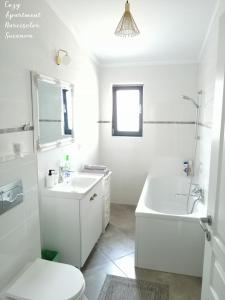 IpoteştiCozy Apartment Narciselor Suceava的白色的浴室设有浴缸、水槽和卫生间。