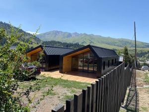 DzhergalanPeak Lodge Jyrgalan的山丘上带木栅栏的房子