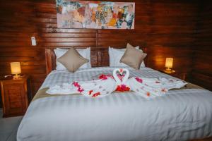 珀尼达岛Kurnia Guest House & Spa的一张白色的床,上面有两只天鹅