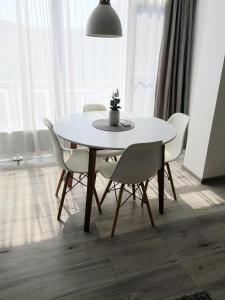 特尔古穆列什Alexa Apartament的餐桌,配有白色椅子和盆栽植物