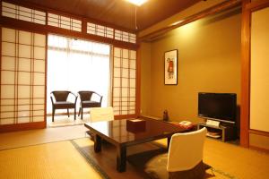丰冈市城崎温泉 旅館 つばき乃 - Kinosaki Onsen Ryokan Tsubakino的客厅配有电视和桌椅