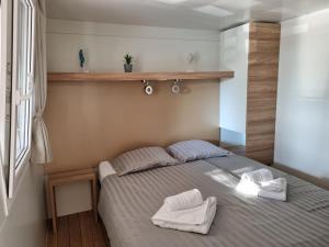 耶泽拉Premium Mobile Home ZEN SPOT 280的一间卧室配有一张床,上面有两条毛巾