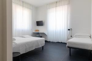 雷卡纳蒂港AMARENA B&B Porto Recanati的配有白色窗帘的客房内的两张床