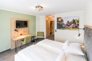 波滕施泰因施万酒店的一间卧室配有一张床、一张书桌和一台电视