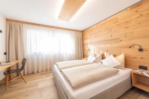 巴迪亚Ciasa Nene Franzl的一间卧室设有一张带木墙的大床