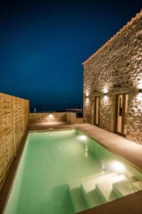 伊西翁Mani Luxury Suites and Studios in Gytheio with Private Pools的夜间房子后院的游泳池