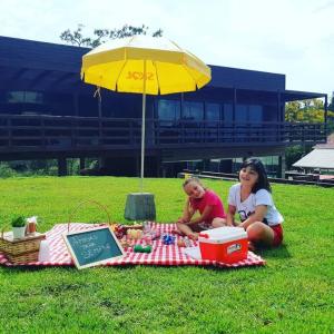 塞尔苏拉穆斯州长镇Pousada Farol do Arvoredo的两个女孩坐在野餐毯上,放在伞下