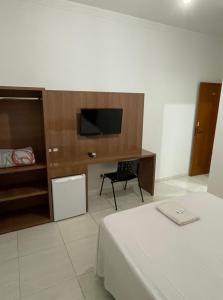 奥托兰迪亚Prime Hotel Hortolândia的一间卧室配有一张床、一台电视和一张书桌