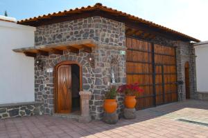 San Martín de las PirámidesLa Casona Pirámides的一座石头建筑,有门和两株盆栽植物