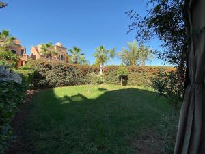 马拉喀什atlas golf resort marrakech " Maison à 03 chambres avec jardin privé "的一座有树 ⁇ 和棕榈树的院子和一座建筑