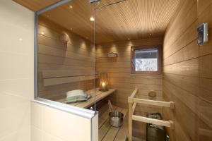 沃卡蒂Vuokatin Aateli Studios的一间设有木镶板和玻璃墙的桑拿浴室