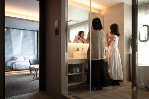 函馆FAV HOTEL HAKODATE的站在浴室镜子前的妇女