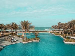 Cam LâmMystery Villas & Spa Cam Ranh的棕榈树和海滩度假村的游泳池