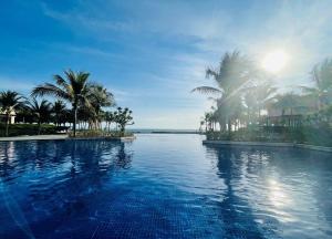 Cam LâmMystery Villas & Spa Cam Ranh的一座棕榈树和海洋游泳池