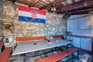 迪斯诺Twin Room Tisno 5128a的厨房配有桌子,石墙上挂着旗帜