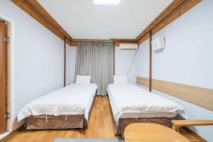 济州市Jeju Miju Hotel的配有木地板和白色墙壁的客房内的两张床