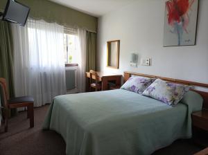 拉科鲁尼亚帕拉斯酒店的一间卧室配有一张床、一张桌子和一个窗户。
