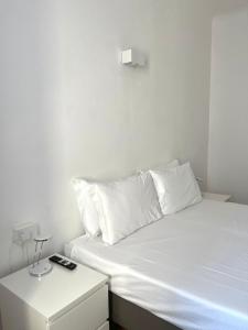 米兰Easy Milano - Rooms and Apartments Navigli的白色的床、白色枕头和床头柜