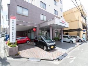 宫崎Tabist Rays Hotel Yakata的停在大楼前停车场的汽车