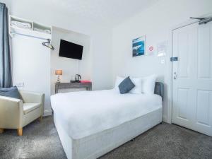 滨海克拉克顿OYO Pier Hotel的白色卧室配有床和椅子