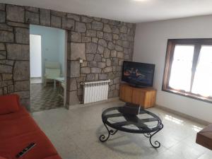 拉弗兰卡Villa Noriega (La Franca)的带沙发和电视的客厅以及石墙。