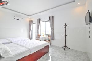 Hoi NghiaRuby Hotel - Tân Uyên - Bình Dương的一间白色卧室,配有床和电视