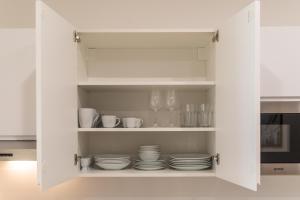 维也纳Vienna City Apartment的白色的厨房橱柜,内有盘子和玻璃杯