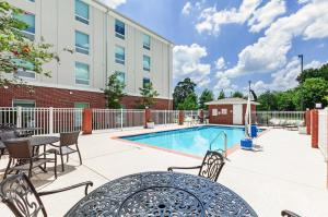 巴吞鲁日Holiday Inn Express & Suites Baton Rouge East, an IHG Hotel的一个带桌椅的庭院和一个游泳池