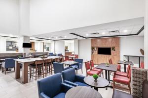 巴吞鲁日Holiday Inn Express & Suites Baton Rouge East, an IHG Hotel的一间配备了桌椅的等候室和无意间