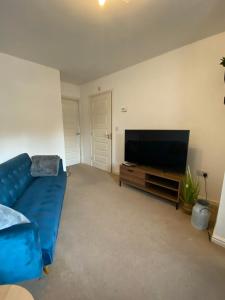 麦斯堡Kingfisher House的客厅配有蓝色的沙发和平面电视。