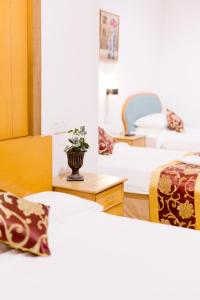 瓜拉丁加奴Villa Sri Mayang的一间设有三张床的房间和一张桌子上的花瓶