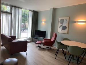 迪温特Stadshotel aan de IJssel in hartje Deventer的客厅配有椅子、桌子和电视