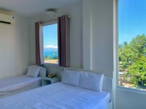 芽庄芽庄绿洲酒店的一间卧室设有两张床和大窗户