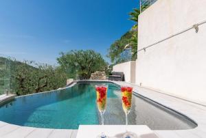 尼斯Villa des Oliviers的两个带鲜花的饮酒杯,在游泳池旁边