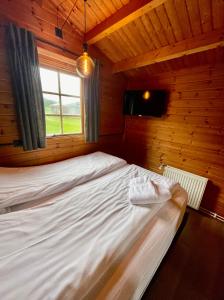 Stærri-Árskógur伊特利维克度假屋的木制客房的一张床位,设有窗户
