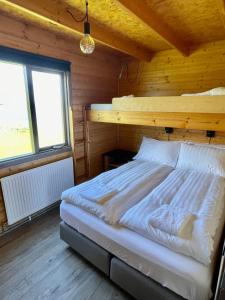 Stærri-Árskógur伊特利维克度假屋的木制客房内的一间卧室,配有一张床