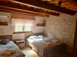 杜布罗夫尼克Gozdarjeva hiška M&K的一间卧室设有两张床和砖墙