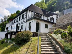 柯尼希施泰因易北Saechsische-Schweiz-Ferienhaus-Wohnung-2-mit-hervorragendem-Panoramablick-ueber-das-Elbtal的一座小山上的白色房子,设有楼梯