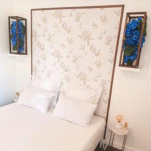 格勒诺布尔Résidence Prestige, Calme & Terrasse Ensoleillée的一张带白色枕头的床和一堵鲜花的墙壁