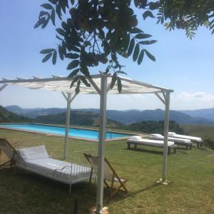 Monte San PietroCa' Lo Spicchio的享有游泳池的景致,设有凉亭和两把椅子