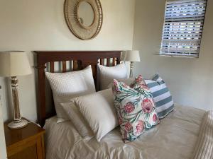 希尔顿Cabbage Tree Cottage的一间卧室配有带枕头和镜子的床